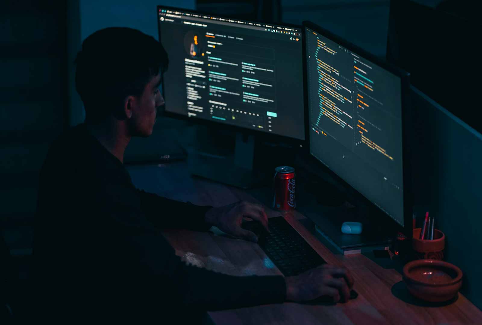 Hackers working in a dark room with multiple monitors